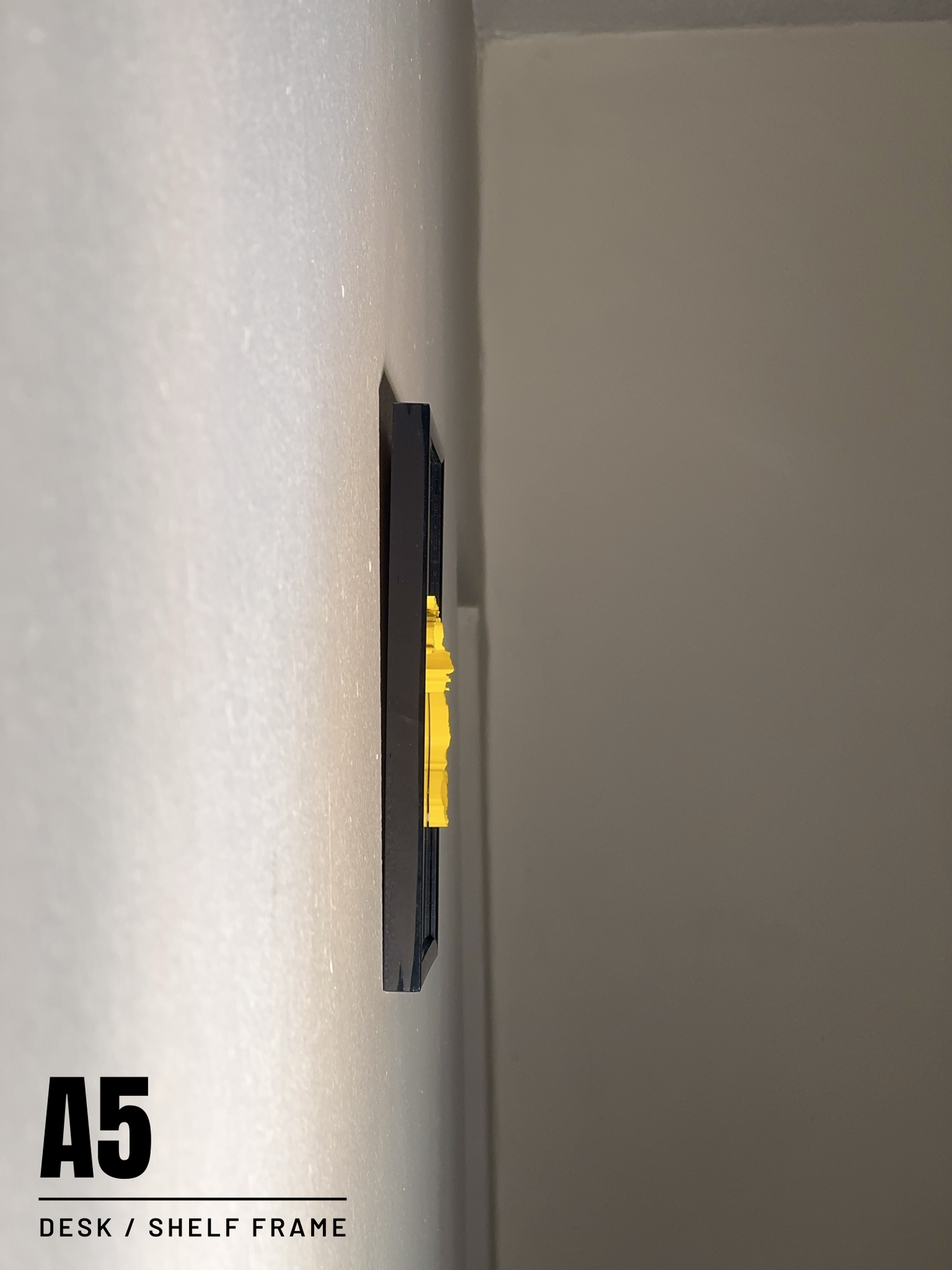 Black desk or shelf frame with a yellow 3D Race Route Profile on a whitewall.